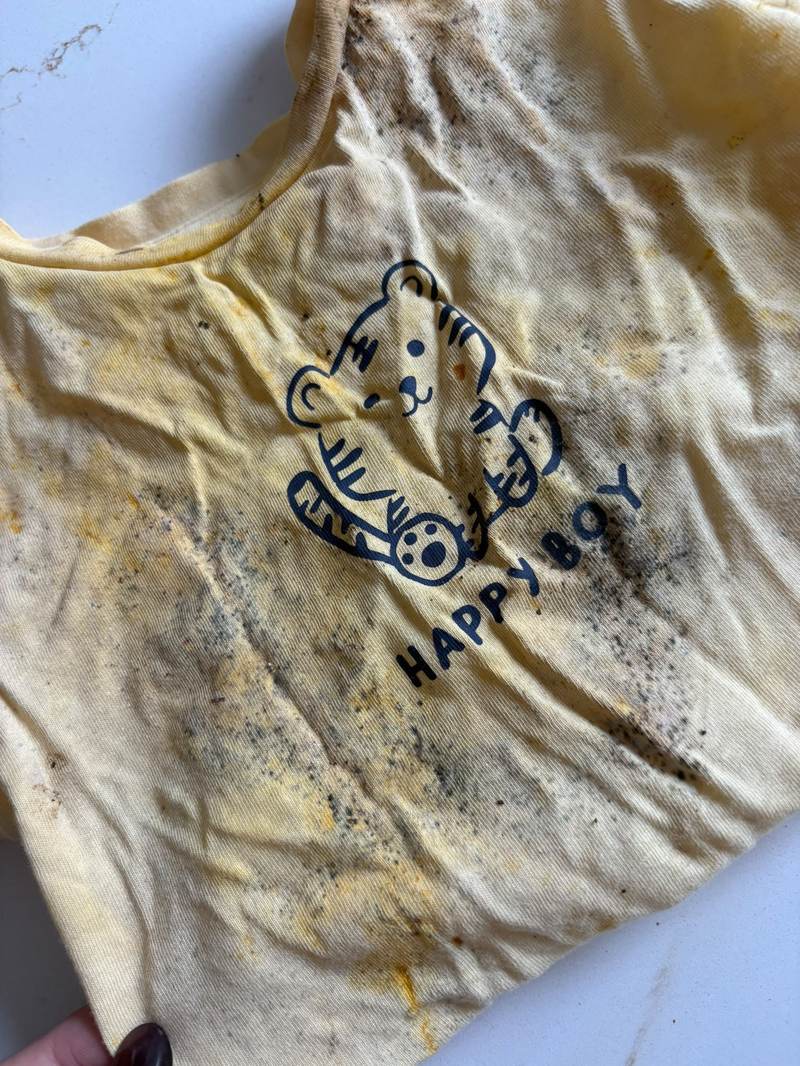 Mold spotting on a child's t-shirt found stored in a drawer, showing dark speckled staining typical of mold or mildew grown on damp fabric